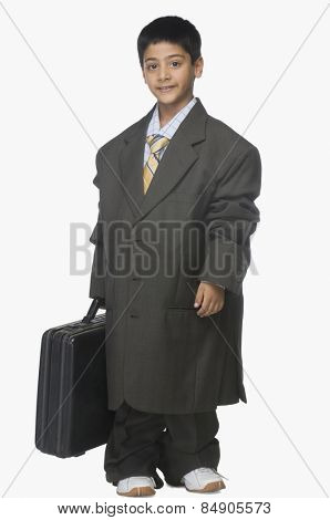 Portrait of a boy wearing oversized suit and holding briefcase