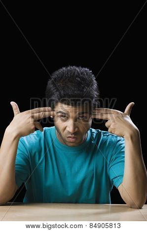 Man making gun signs with fingers at his temples