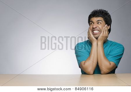 Man looking angry with his head in his hands