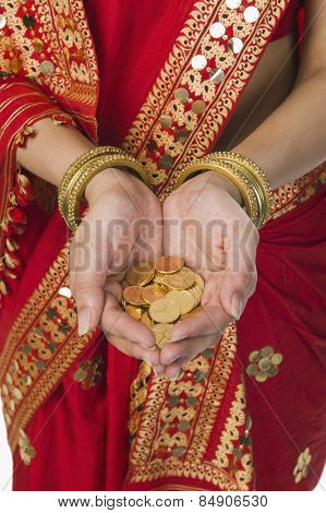 Woman in bright red mekhla holding gold coins