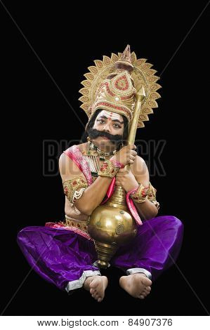 Man dressed-up as Ravana the Hindu mythological character and holding a mace
