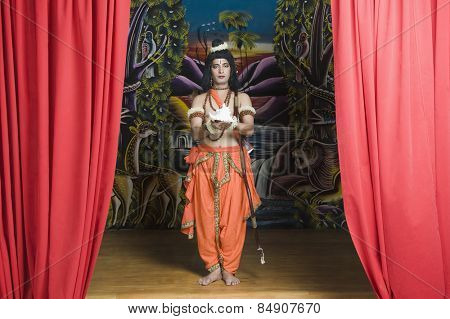 Man dressed-up as Rama holding a conch shell
