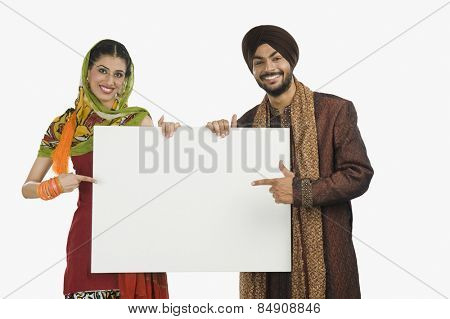 Portrait of a Sikh couple holding a blank placard