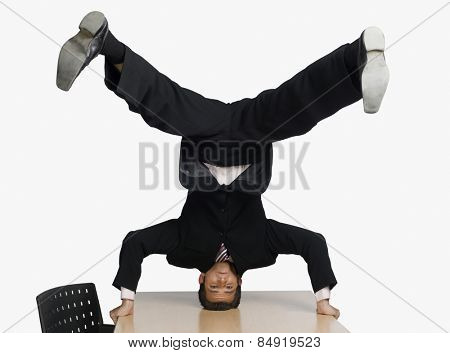 Businessman doing headstand on a conference table