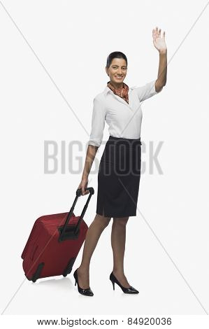Air hostess carrying her luggage and waving