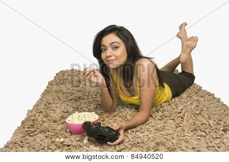 Portrait of a woman eating popcorn and playing video game