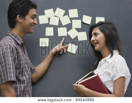 College students smiling in front of a bulletin board