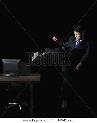 Frustrated businessman kicking a desktop pc