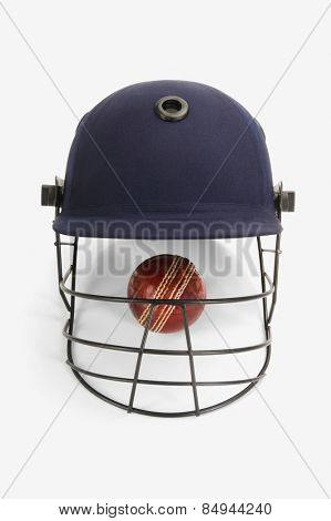 Close-up of a cricket ball under a cricket helmet