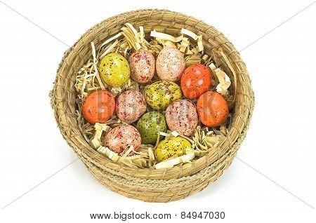 Colorful painted easter eggs in brown basket isolated on white background