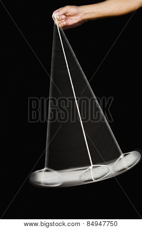 Close-up of a person's hand swinging a stone pendulum