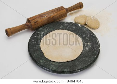 Close-up of a rolling pin and a board with chapatti (Indian flatbread) and dough