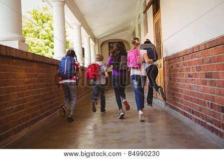 Full length rear view of school kids running in school corridor