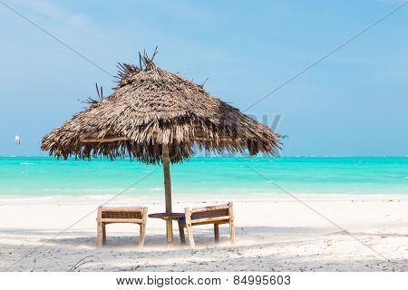 Two deck chairs and umbrella on tropical beach.