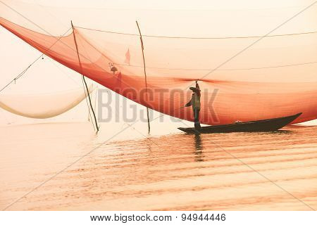 Unidentified fisher man check his nets in early morning on river in Hoian, Vietnam.