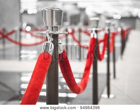 Red Carpet Fence Pole With Red Ropes Blurred Interior Background