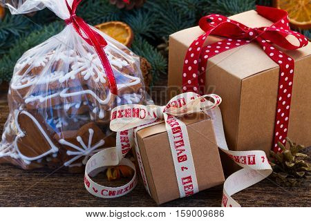 christmas gingerbread cookies in transparent bag with fir tree and gift boxes on wooden table close iup