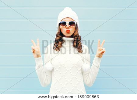 Fashion Woman Blowing Red Lips Makes Air Kiss Wearing A Heart Shape Sunglasses, Knitted Hat, Sweater