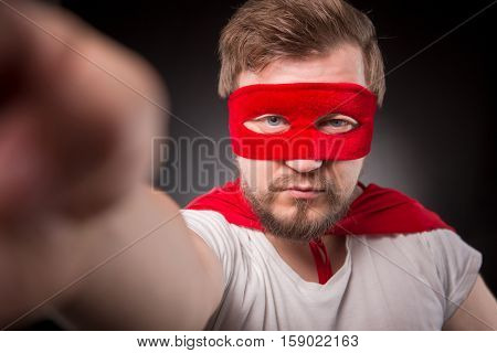 Egoist. Self. Hero. Super Hero. Closeup picture of super hero man with red mask on making photos isolated on black background in studio.