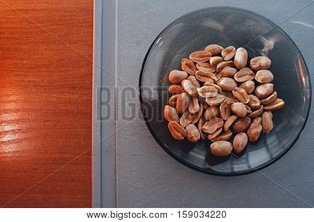 Roasted salted peanuts in a plate on old wooden tableon Board