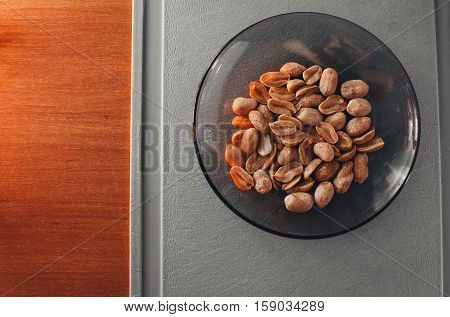 Roasted salted peanuts in a plate on old wooden tableon Board