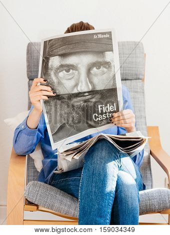 PARIS FRANCE - NOV 29 2016: Woman reading Le Monde newspaper with headline and portrait of Fidel Castro Cuban President - dead on November 25 2016