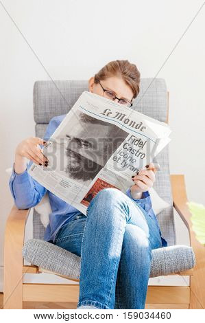 PARIS FRANCE - NOV 29 2016: Woman reading Le Monde newspaper with headline and articles about Fidel Castro Cuban President - dead on November 25 2016