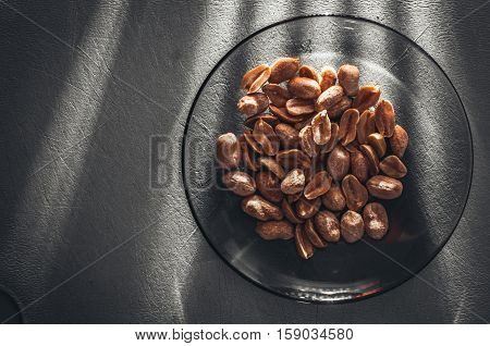 Roasted salted peanuts in a plate on old wooden table, on Board