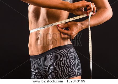 Dieting concepts. Sports woman using meter stick for her body. Fitness lady measuring her waist after or before training in gym in studio.