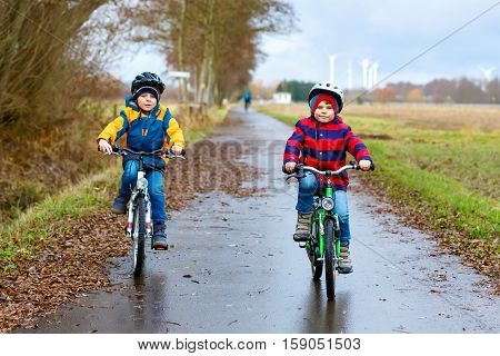 Two active kids boys in helmet biking on bicycles. Happy children in colorful clothes and city traffic. Safety and protection for preschool kids. Friends making sports, acitve leisure.