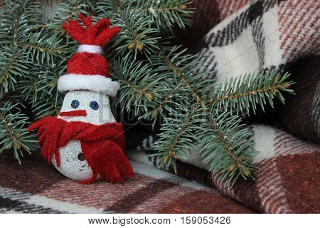 Snowman made from light bulb near Christmas tree
