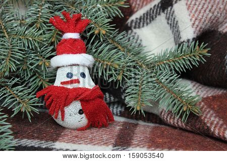 Snowman made from light bulb near Christmas tree