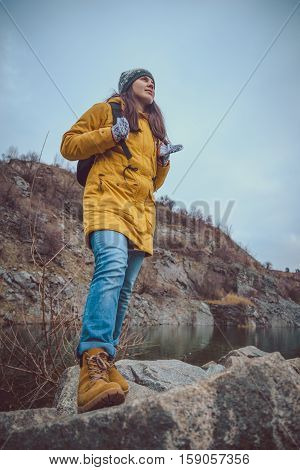Active female hiker resting near lake on rocks beach