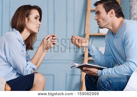Speak about your problems. Desperate young woman feeling depressed and sitting in the arm chair while solving her problems with professioanl psychotherapist