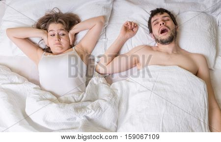 Snoring Concept. Young Woman Is Covering Her Ears. Man Is Snorin