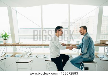 Men Are Sitting At Table In Modern Cafe