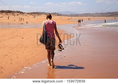 LIENCRES DUNES SPAIN - AUGUST 21: Woman walking in the water edge of the Liencres dunes nature reserve in the Cantabrian sea on August 21 2016