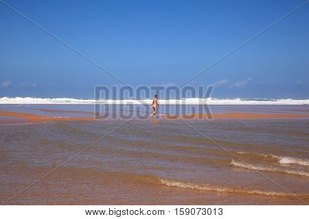 LIENCRES DUNES SPAIN - AUGUST 21: Woman walking in the water edge of the Liencres dunes nature reserve in the Cantabrian sea on August 21 2016