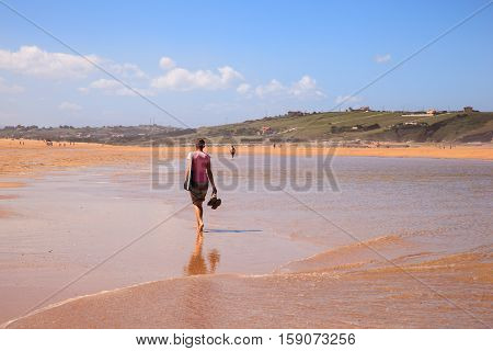LIENCRES DUNES SPAIN - AUGUST 21: Woman walking in the water edge of the Liencres dunes nature reserve in the Cantabrian sea on August 21 2016