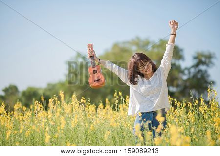 .young Woman Playing On Ukulele On Sunhemp Background