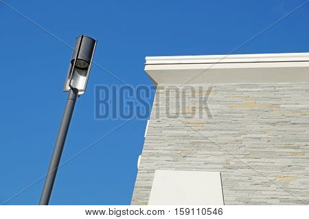 Closeup of a modern white metallic street lamppost with five lanterns against clear blue sky.