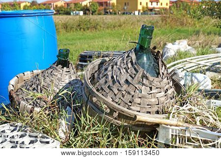 Old demijohn glass wrapped in wicker abandoned