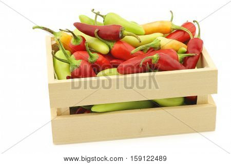 red and green rawit peppers (Capsicum annuum 'Bird's Eye') in a wooden box on a white background