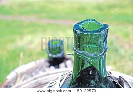 Old demijohn glass wrapped in wicker abandoned