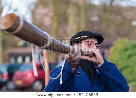OLDENZAAL NETHERLANDS - NOVEMBER 27 2016: Unknown man blowing a so called "midwinterhorn" a traditional handmade wooden instument. It is used in the advent period in some eastern parts of the netherlands