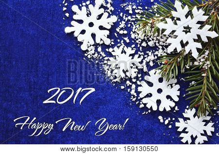 Happy New Year 2017 greeting card. Happy New Year decoration with snowflakes and fir tree branch on blue background.Selective focus.