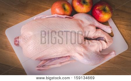 Raw duck carcass prepared for roasting. Whole raw duck ready to cook. Fresh raw duck carcass on wooden cutting board.