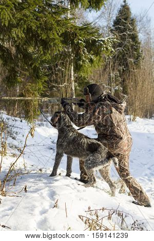 Hunter in camouflage aiming. with a dog. vertical shot