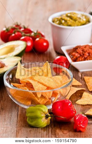 Guacamole and nacho chips on glass bowl.
