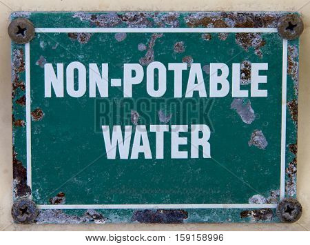 An old green and white non potable water sign.